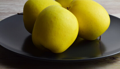 Close up, yellow apples on dark plate.