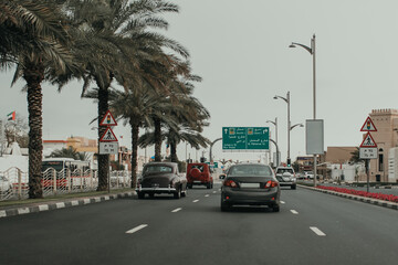 Dubai Jumeirah road car traffic with many cars, direction road boards, palm trees, traffic lights and sightseeing objects