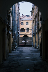 view on a narrow street that goes to a dead-end from an arch of a building