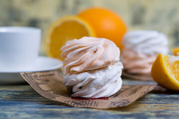 Delicious marshmallow with orange filling close up, coffee and cut orange on blue background