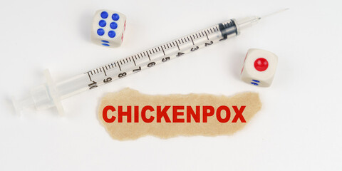 On a white surface lies a syringe, dice and a piece of paper with the inscription - CHICKENPOX