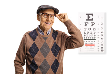 Elderly man wearing glasses and standing in front of an eye examination test