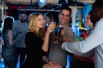 Group of friends clinking glasses with cocktails at night club
