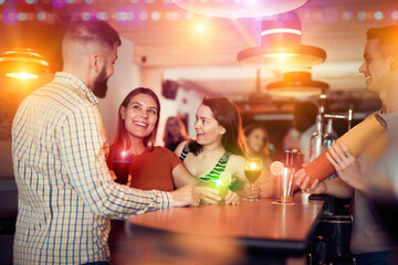 Portrait of happy people and bartender shaking cocktail mixer in nightclub