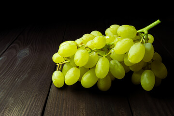 bunch of green grapes on dark wooden background