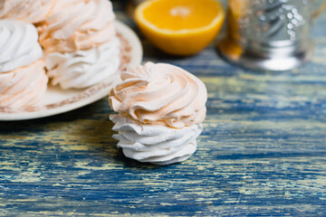 Appetizing marshmallow close-up and a cut orange on a blue table, background with copy space