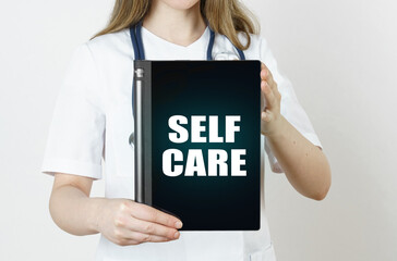 Fototapeta na wymiar The doctor is holding a tablet with the inscription - Self Care