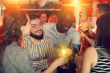 Smiling people talking with drinks in the hand in the nightclub. High quality photo