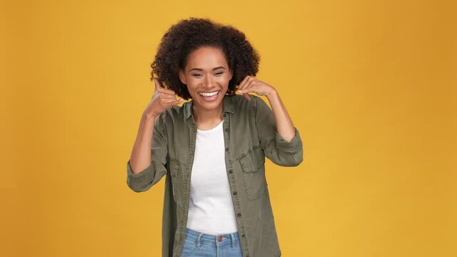 Funky lady show hands sign call friend point isolated mustard color background