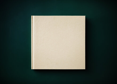 Blank closed hardcover book on green background. Flat lay.