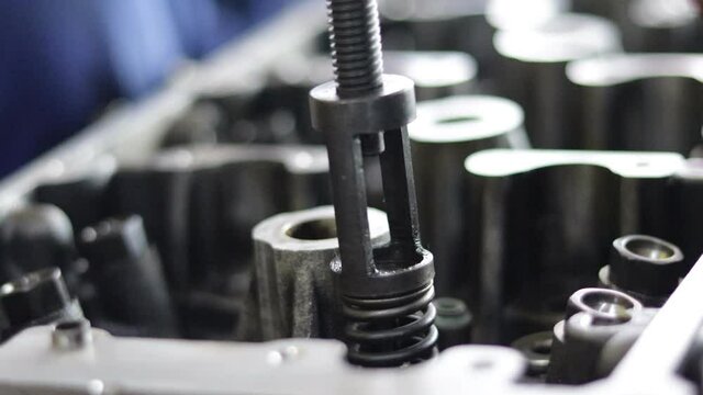 the hand of a mechanic is installing the valve seal of an overhauled car engine