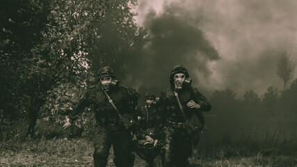 Naklejka premium Soldiers carrying an injured solder in gas masks during military training