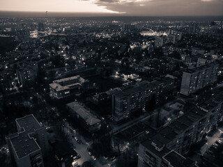 Aerial night city streets with lights. Pavlove pole, Kharkiv Ukraine. Multistory buildings scenic dark view. Urban moody grayscale background