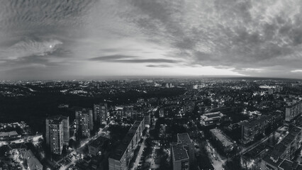 Night lights on streets of residential district and moody cloudy sky. Aerial grayscale sunset scenic panorama on Kharkiv city, Pavlove pole