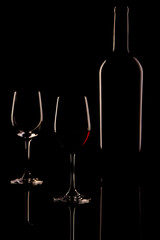 two wine glasses and a wine bottle with light edges against a black background