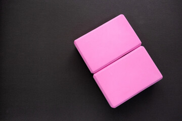 Two pink yoga blocks on a dark gray background. Top view and copy spase