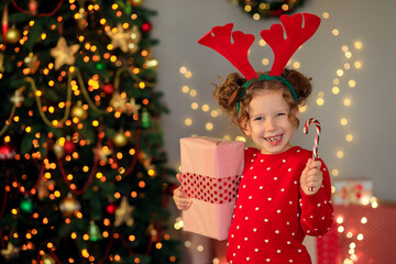 cheerful funny little girl baby with new year gifts by the tree