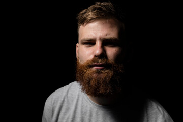 Close-up portrait of a handsome a brunette brutal bearded man in a grey t-shirt. Stylish and handsome man with a beard.
