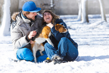 Young family, couple in love on a winter walk with a beagle puppy.