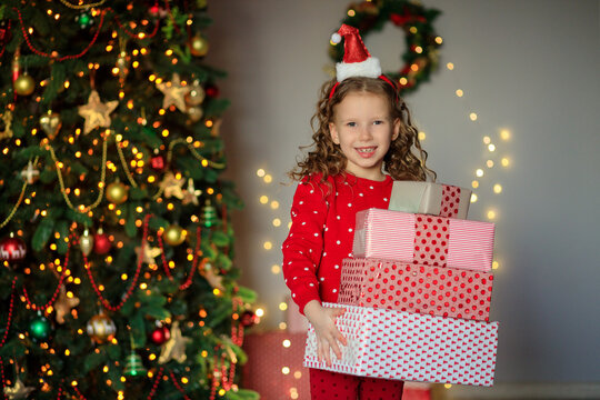 cheerful funny little girl baby with new year gifts by the tree
