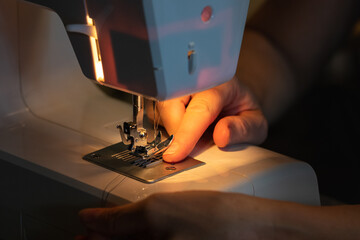 woman's hands sew on a sewing machine, close up, working process.