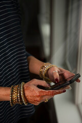 Woman's hands with henna typing on phone 