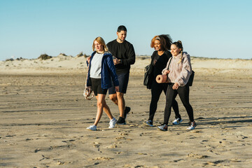 Yoga instructor and three multiethnic people walking on the beach