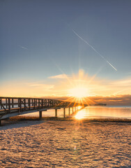Fototapeta na wymiar Wooden pier with sunstar on Bjarred beach in south Sweden.