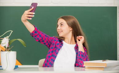 happy child making selfie. school blogger. vlogger with cellphone in classroom.