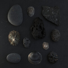 Flat lay arrangements of pebbles and limpet shells collected on beaches of Gran Canaria, 
on black slate board