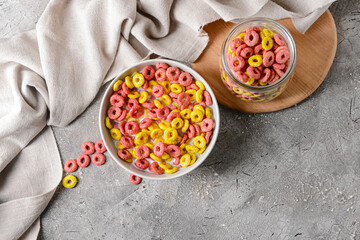 Bowl with crunchy corn flakes rings and milk on grunge background