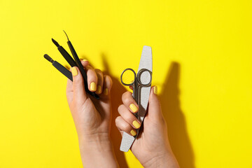 Female hands with manicure equipment on yellow background