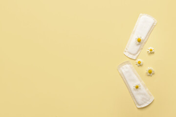 Menstrual pads and chamomile flowers on yellow background