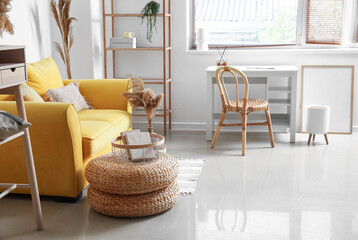 Interior of stylish living room with yellow sofa, workplace and dry reeds