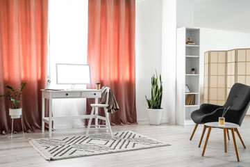 Interior of light room with modern workplace and red curtains