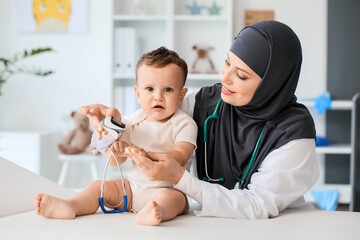 Muslim pediatrician examining baby boy in clinic