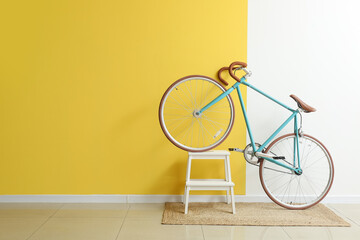Modern bicycle with stepladder near yellow and white wall