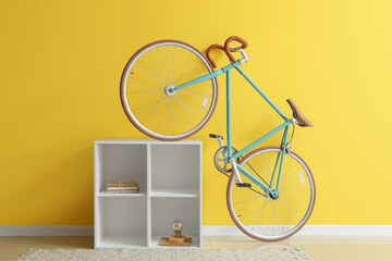 Modern bicycle and shelving unit near yellow wall
