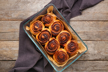 Baking dish with tasty cinnamon rolls on wooden background