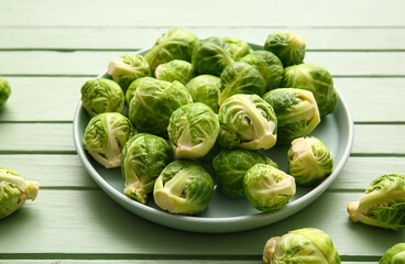 Plate with fresh raw Brussels cabbage on color wooden background