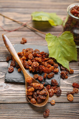Slate plate with tasty raisins on wooden background, closeup