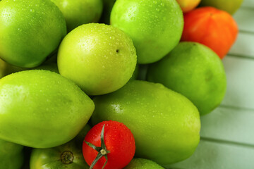 Green and ripe tomatoes on color wooden background, closeup