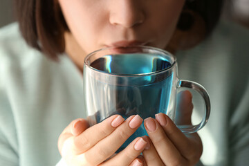 Woman drinking butterfly pea flower tea, closeup