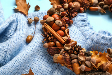 Beautiful acorn wreath and sweater on blue background, closeup