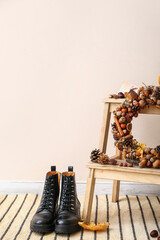 Beautiful acorn wreath on step ladder and boots near light wall