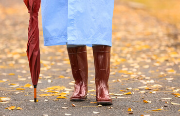 Young woman wearing gumboots in park on autumn day