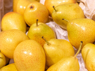 Yellow pears are in a box of white paper. Selling fruit at a grocery store, market, or grocery store. Healthy lifestyle. Fresh fruits