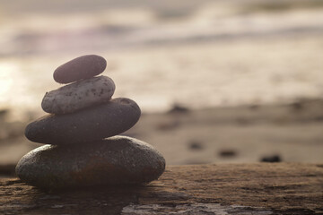 Fototapeta na wymiar zen balancing stones on a wood with a coast background