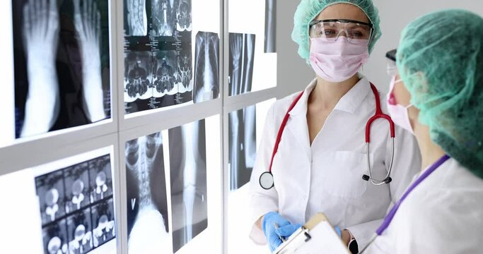 Women doctors in protective masks and glasses looking at xrays in clinic 4k movie slow motion
