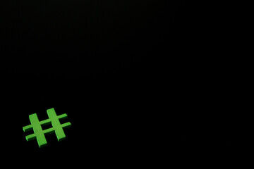 Green wooden symbol Hashtag "#" on blsck background and copy space